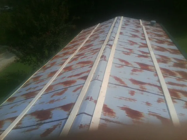 Rusted metal roof panels with new wood purlins before replacement — Storm Damage Roof Repair in Cameron by Roofing Brothers